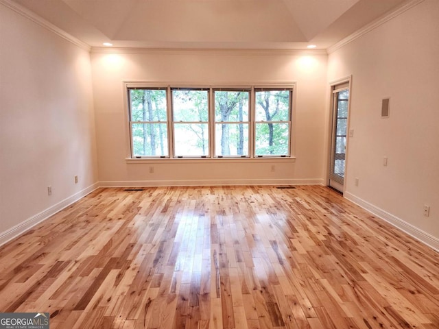 empty room with ornamental molding, a healthy amount of sunlight, light wood-style floors, and baseboards