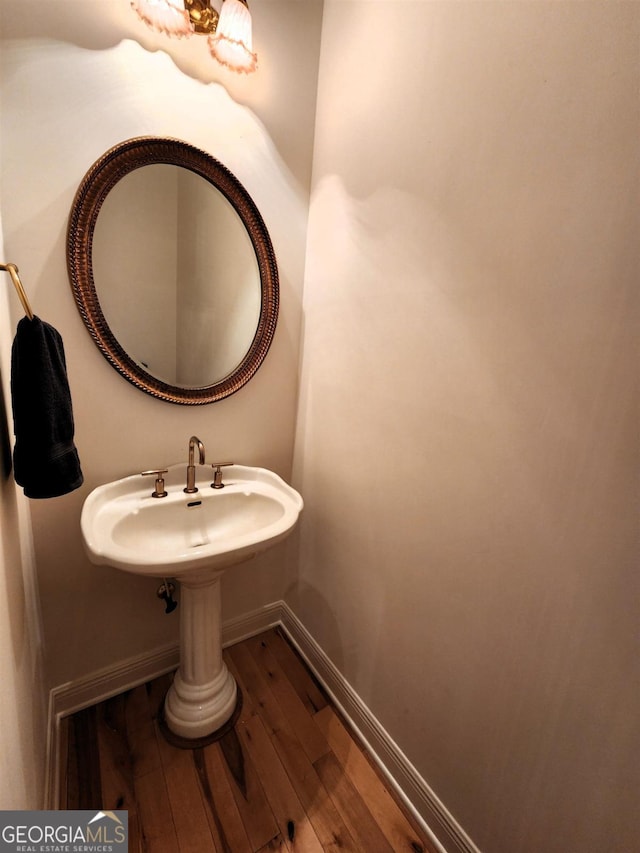 bathroom featuring a sink, baseboards, and hardwood / wood-style flooring