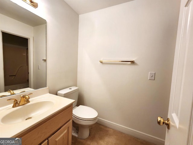 bathroom with toilet, vanity, and baseboards