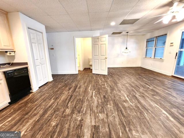 interior space with dark wood-style flooring, a drop ceiling, a ceiling fan, and baseboards