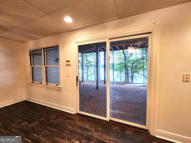 doorway with a paneled ceiling and baseboards