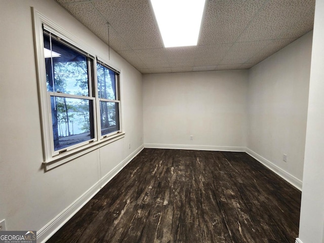 unfurnished room featuring a drop ceiling, baseboards, and wood finished floors