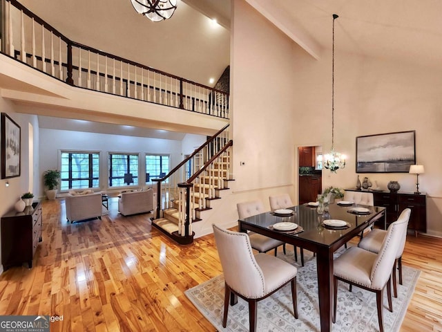 dining space featuring a chandelier, high vaulted ceiling, stairway, and light wood-style floors