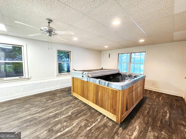 interior space featuring dark wood finished floors, a paneled ceiling, recessed lighting, a hot tub, and baseboards