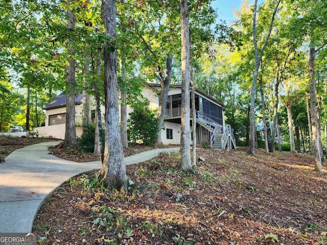 view of home's exterior with driveway, a garage, and stairs