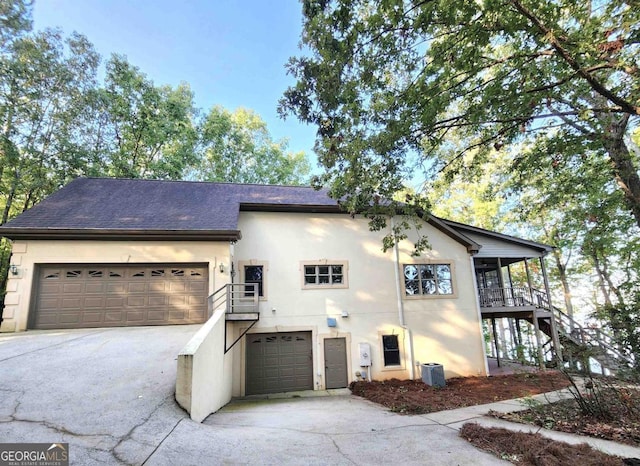 view of front of home featuring driveway, a shingled roof, stairs, central air condition unit, and stucco siding