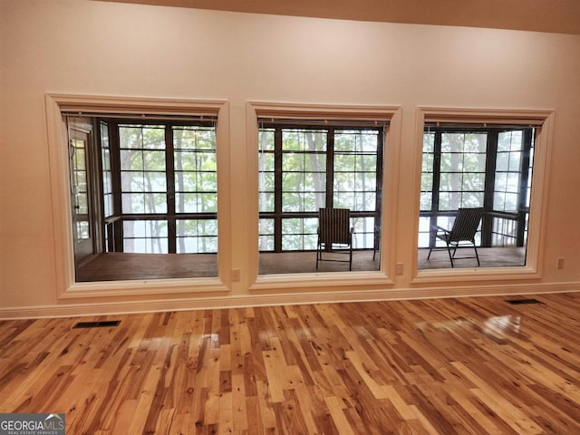 doorway with plenty of natural light, wood finished floors, and visible vents