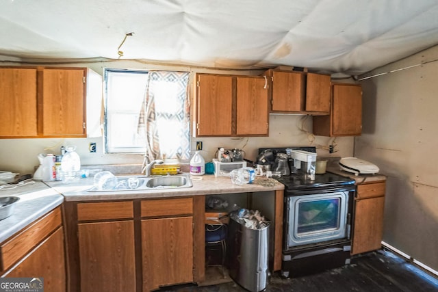 kitchen with brown cabinets, light countertops, dark wood-type flooring, a sink, and range