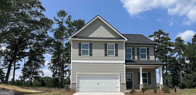 craftsman-style home with a garage, brick siding, driveway, and a porch