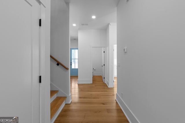 hallway featuring baseboards, visible vents, stairway, light wood-type flooring, and recessed lighting