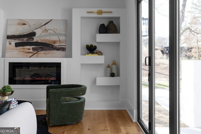 living area with a glass covered fireplace and wood finished floors