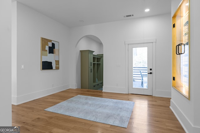 entrance foyer featuring arched walkways, light wood finished floors, recessed lighting, visible vents, and baseboards