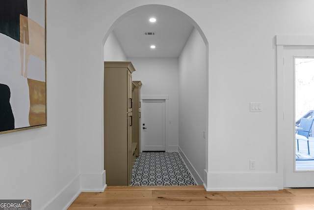 corridor featuring arched walkways, recessed lighting, wood finished floors, and baseboards