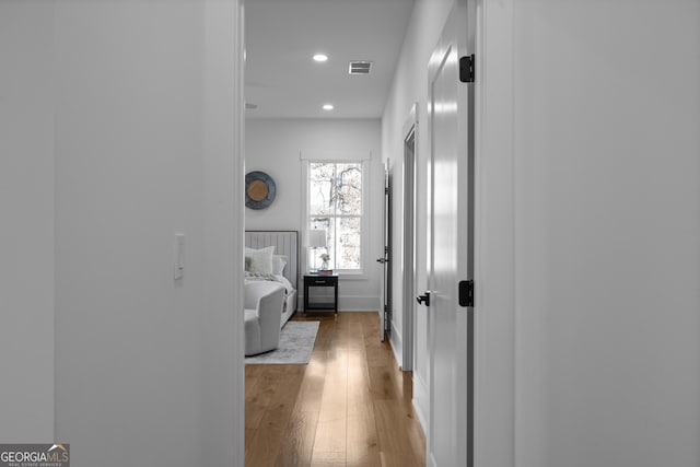 corridor with light wood-style floors, baseboards, visible vents, and recessed lighting