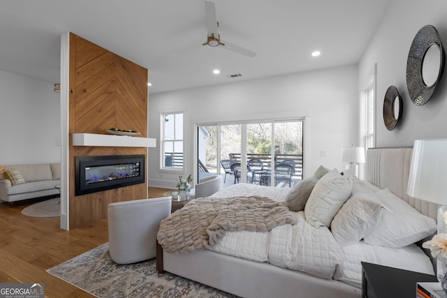 bedroom with a large fireplace, multiple windows, wood finished floors, and recessed lighting