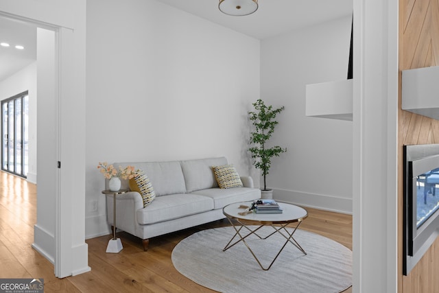 living area with a fireplace, baseboards, and wood finished floors