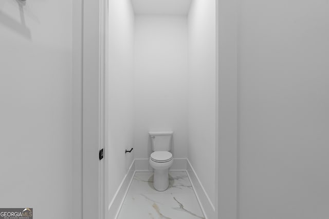 bathroom with toilet, marble finish floor, and baseboards