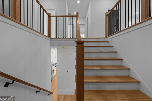 stairs with a high ceiling and wood finished floors