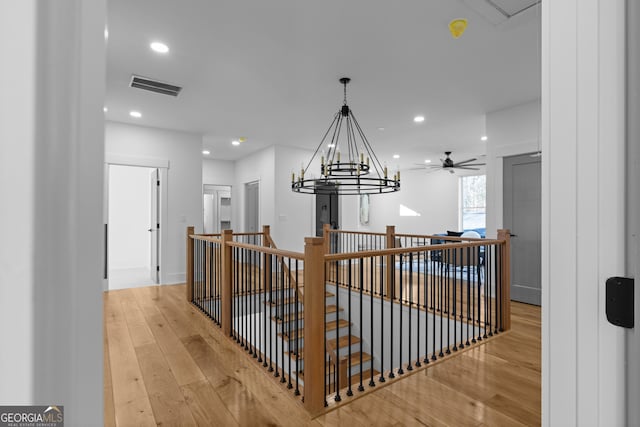 corridor with recessed lighting, visible vents, light wood-style flooring, and an upstairs landing