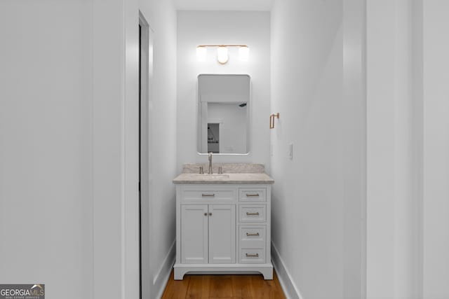 bathroom featuring baseboards, wood finished floors, and vanity