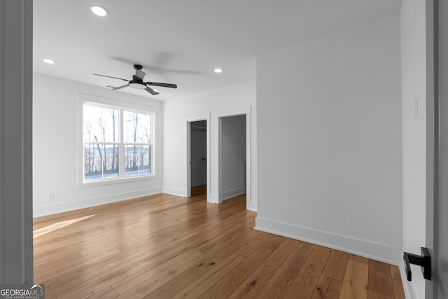 unfurnished bedroom with recessed lighting, a spacious closet, hardwood / wood-style floors, a ceiling fan, and baseboards