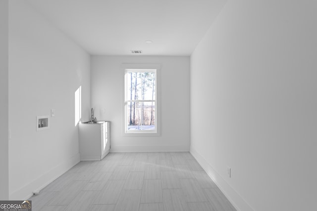 unfurnished room featuring a sink, visible vents, and baseboards