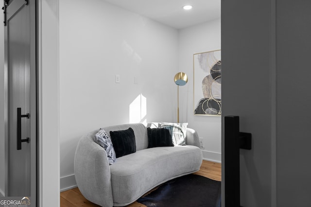 sitting room with recessed lighting, wood finished floors, baseboards, and a barn door