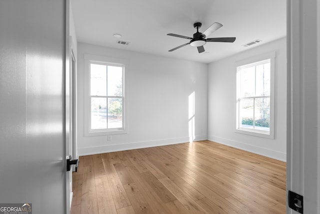 unfurnished room featuring light wood-style floors, baseboards, visible vents, and ceiling fan