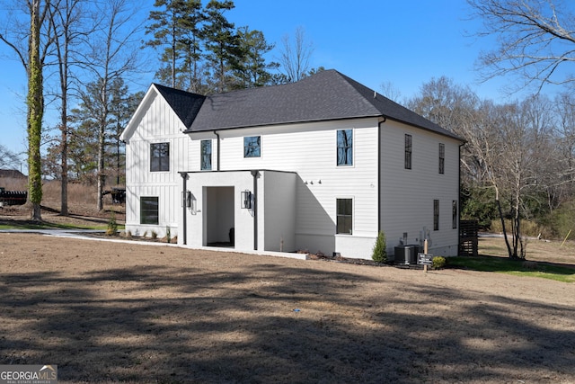 view of front of home featuring board and batten siding, a front yard, a shingled roof, and central AC unit