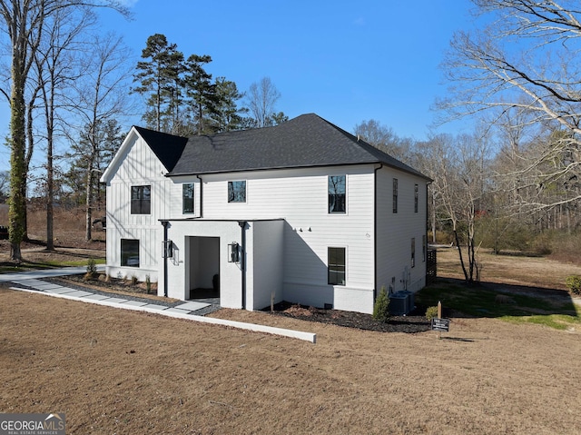 exterior space featuring board and batten siding, roof with shingles, a front lawn, and central air condition unit