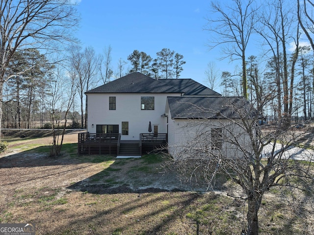 back of property featuring a shingled roof, a deck, and a yard