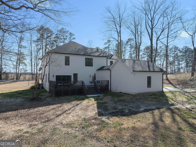 rear view of house featuring a shingled roof and a wooden deck