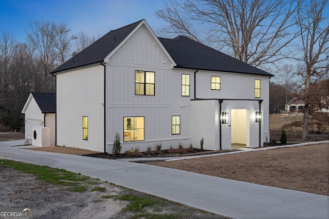 modern farmhouse style home with board and batten siding, brick siding, and a shingled roof