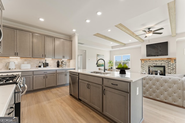 kitchen featuring a sink, open floor plan, appliances with stainless steel finishes, light wood-type flooring, and beam ceiling