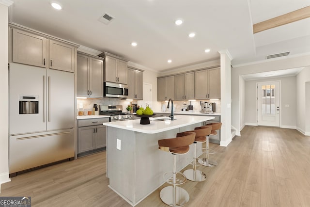 kitchen featuring tasteful backsplash, appliances with stainless steel finishes, a sink, and gray cabinetry