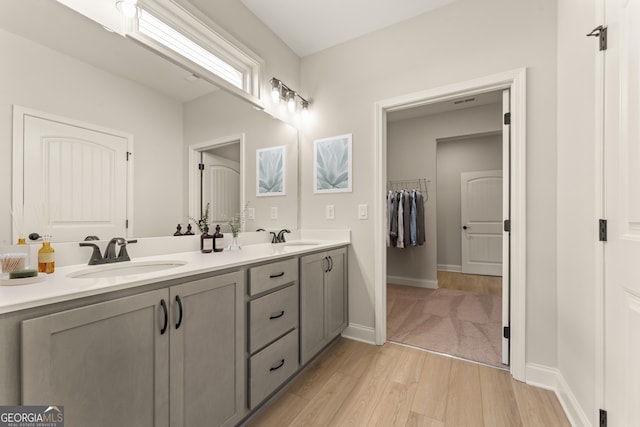 bathroom with double vanity, a sink, baseboards, and wood finished floors