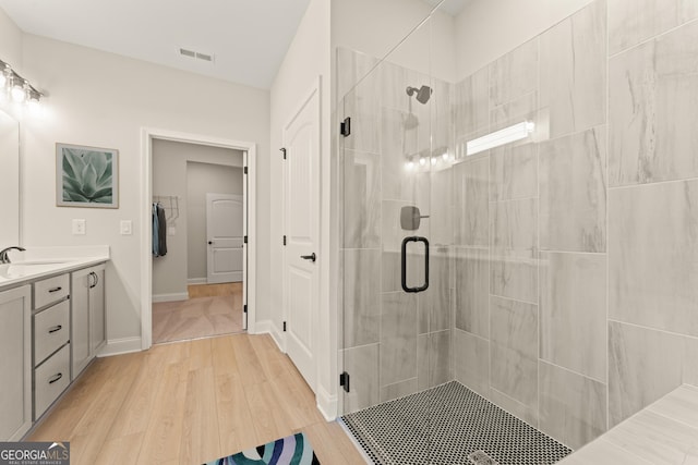 bathroom with a stall shower, visible vents, vanity, and wood finished floors