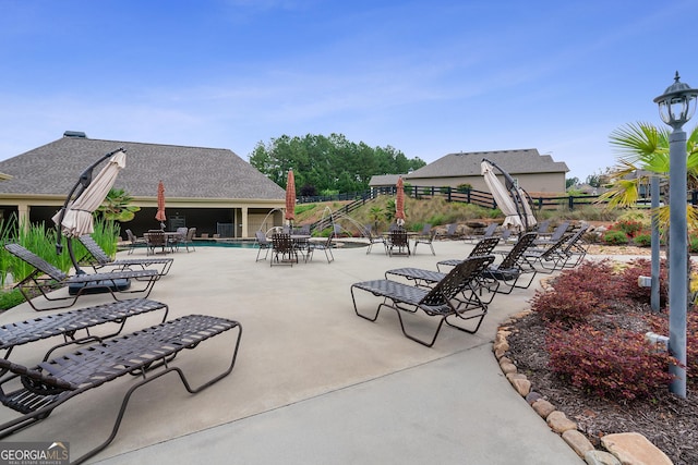 view of patio with a community pool and fence