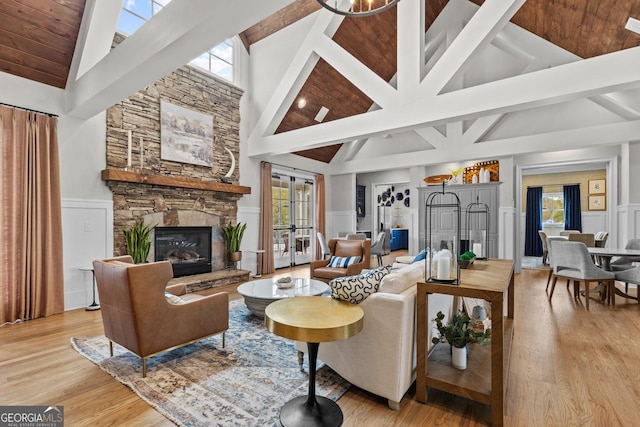 living room with light wood finished floors, wainscoting, a decorative wall, and a stone fireplace