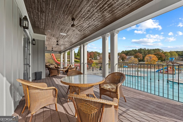 wooden terrace with ceiling fan and a community pool