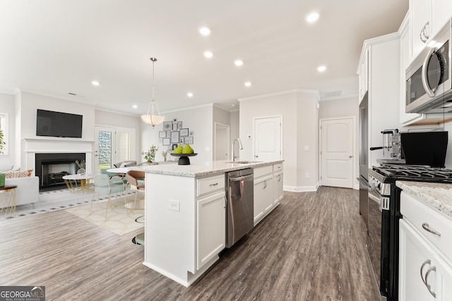 kitchen featuring an island with sink, appliances with stainless steel finishes, open floor plan, a fireplace, and a sink