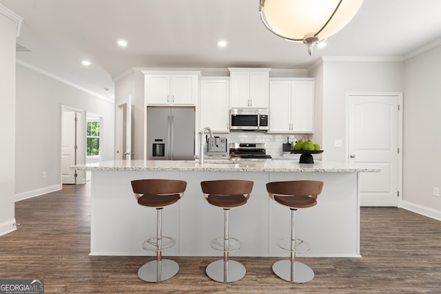 kitchen with a kitchen island with sink, stainless steel appliances, white cabinets, tasteful backsplash, and crown molding