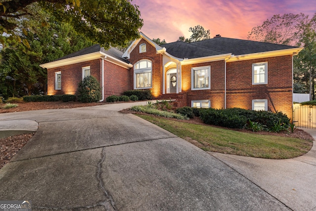 view of front of property featuring a gate, brick siding, driveway, and fence