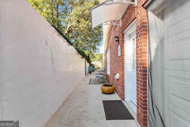 view of property exterior with a patio area, fence, and brick siding