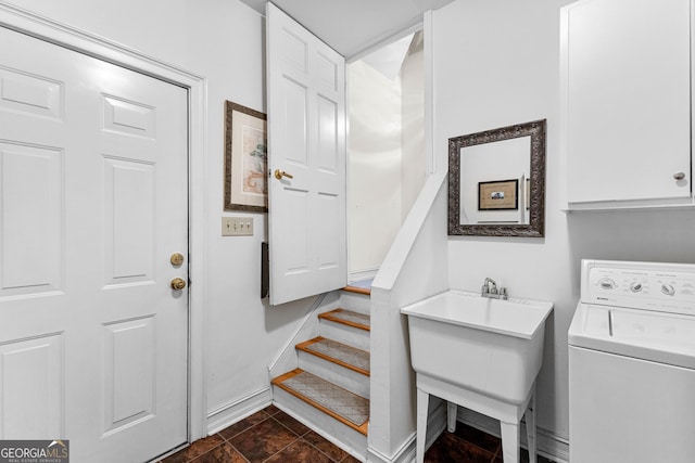 washroom with washer / dryer, cabinet space, a sink, and baseboards