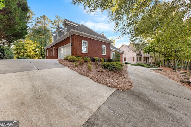 view of home's exterior with a garage, brick siding, and driveway