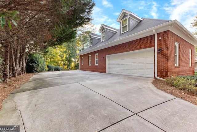 view of side of home featuring concrete driveway, brick siding, and an attached garage