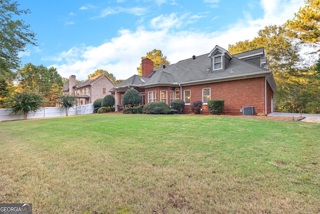 back of property with brick siding, a lawn, cooling unit, and fence