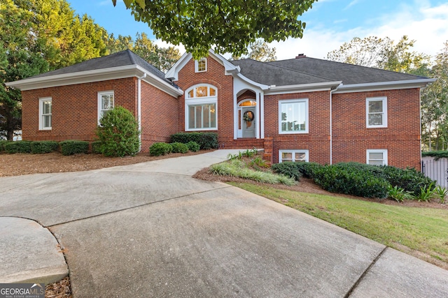 view of front of property featuring driveway, brick siding, and roof with shingles