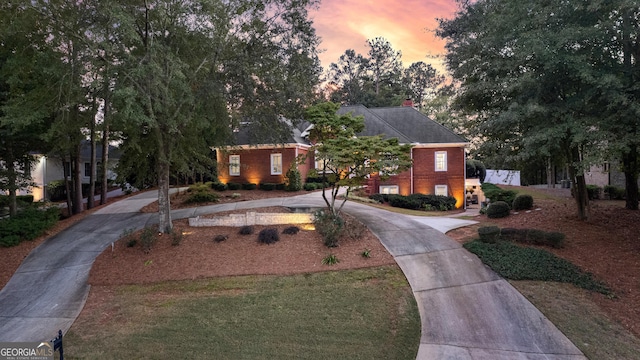 view of front of home with driveway, brick siding, and a front yard